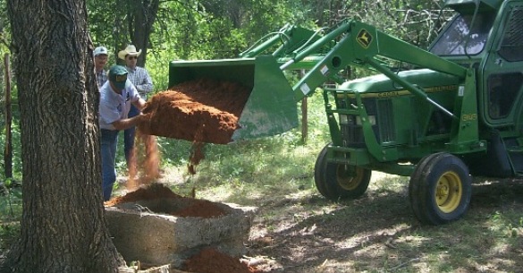 Filing an abandoned well with a clay mixture per plugging procedures.
